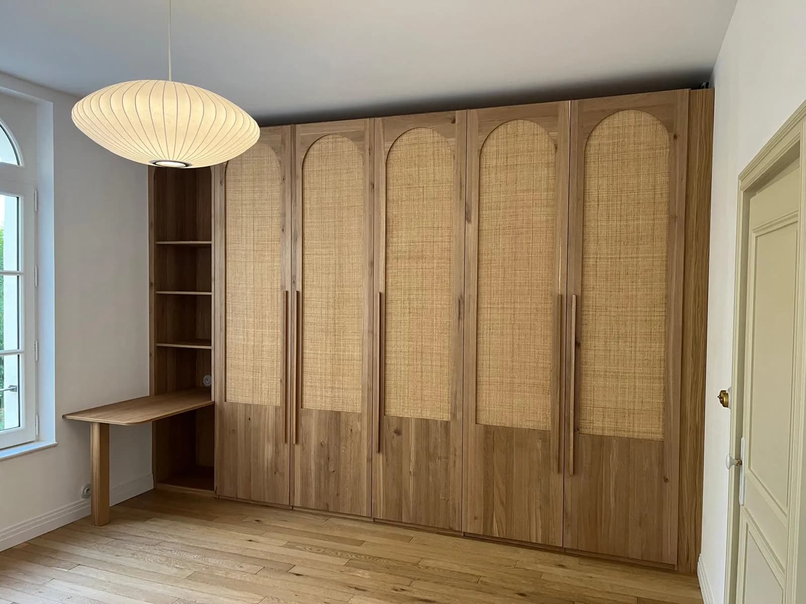 Armoire toute hauteur en chêne avec façades en cannage à arches, étagères ouvertes et bureau intégré